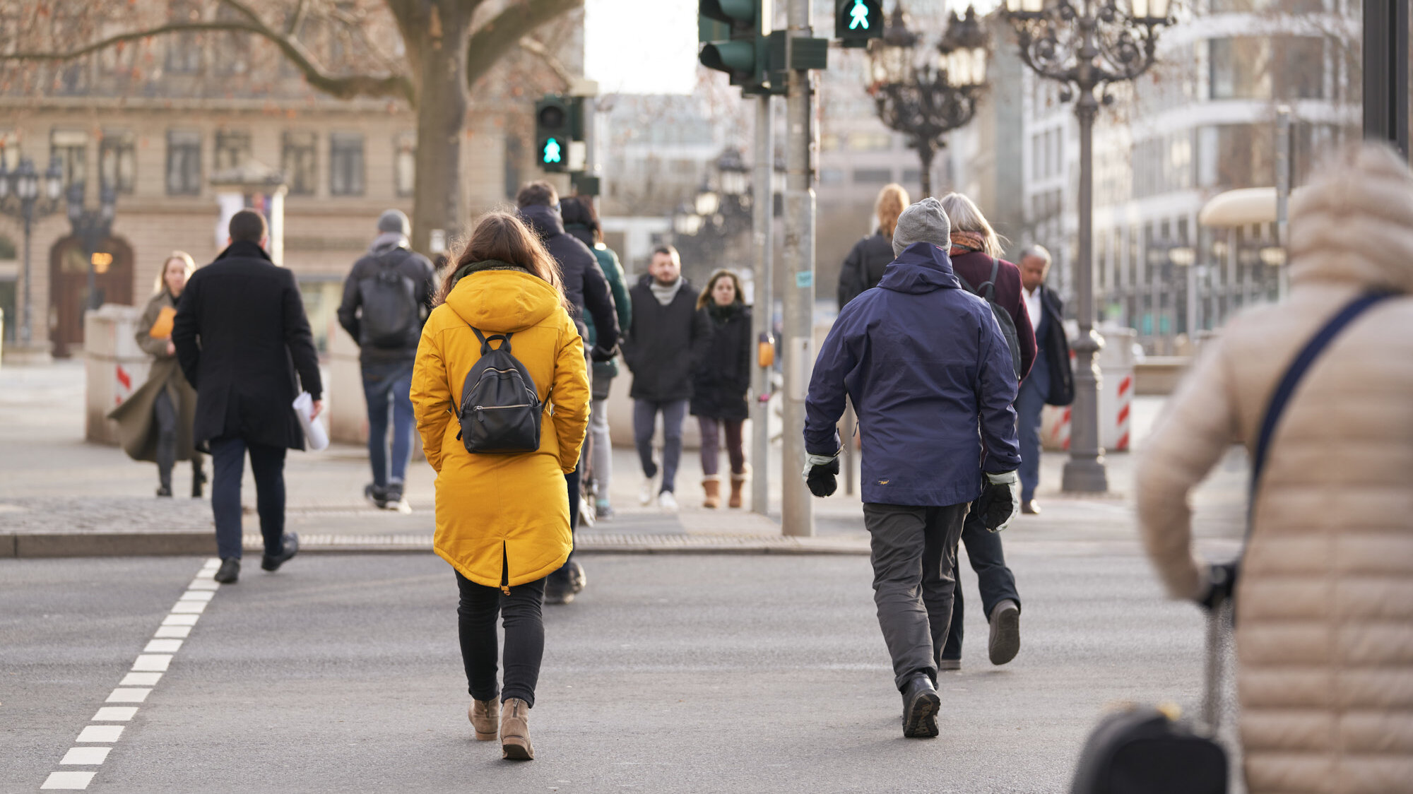 Mehrere Menschen queren eine Straße an eine Fußgängerampel, die auf grün steht.