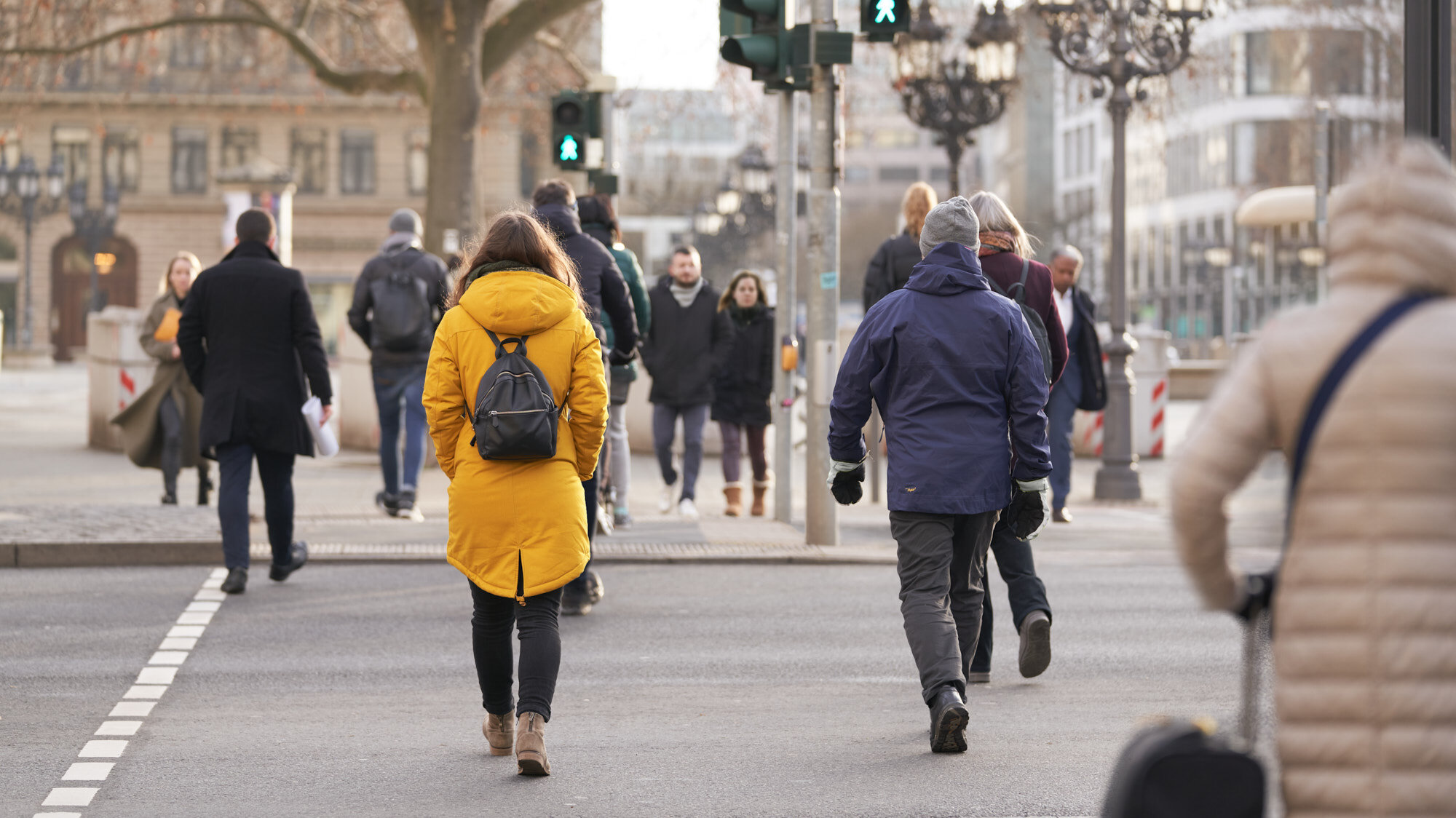 Mehrere Menschen queren eine Straße an eine Fußgängerampel, die auf grün steht.