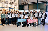 Gruppenfoto von vielen Menschen mit Urkunden in den Händen