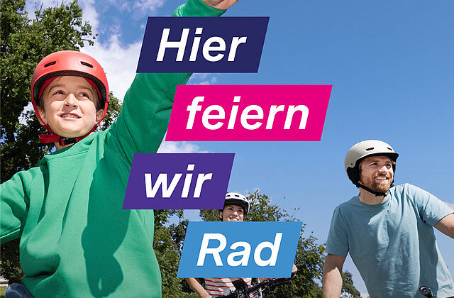 Drei Personen mit Fahrradhelmen auf Fahrrädern, eine Person zeigt mit ausgestrecktem Arm nach oben, blauer Himmel und Bäume im Hintergrund, Text 'Hier feiern wir Rad'