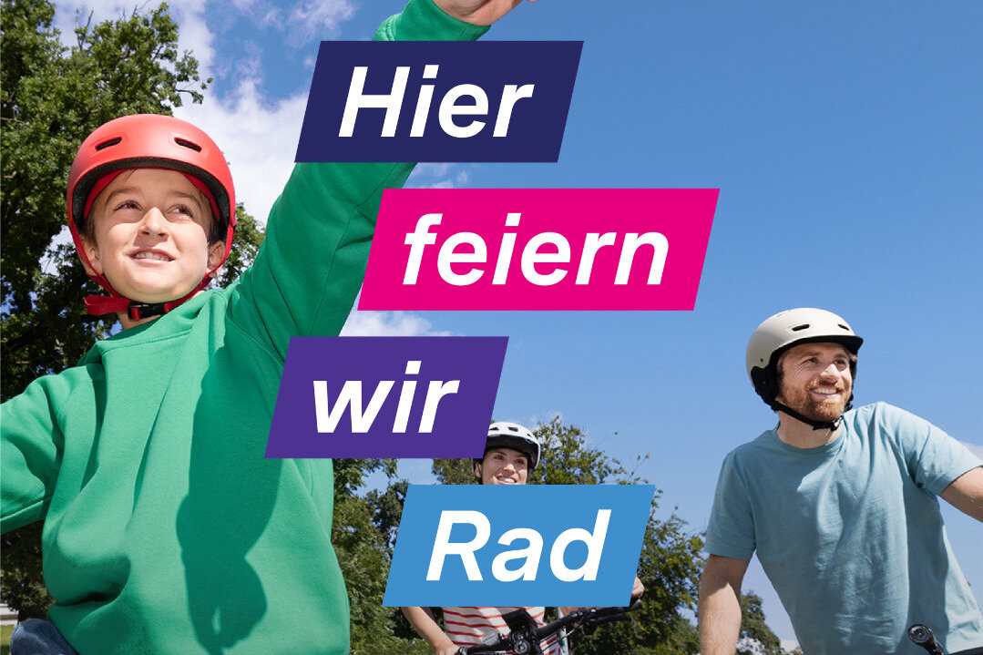 Drei Personen mit Fahrradhelmen auf Fahrrädern, eine Person zeigt mit ausgestrecktem Arm nach oben, blauer Himmel und Bäume im Hintergrund, Text 'Hier feiern wir Rad'