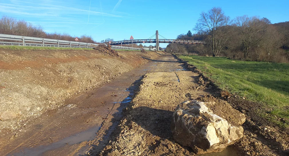 Foto: Ein matschiger Unterbau eines Radwegs neben einer Wiese
