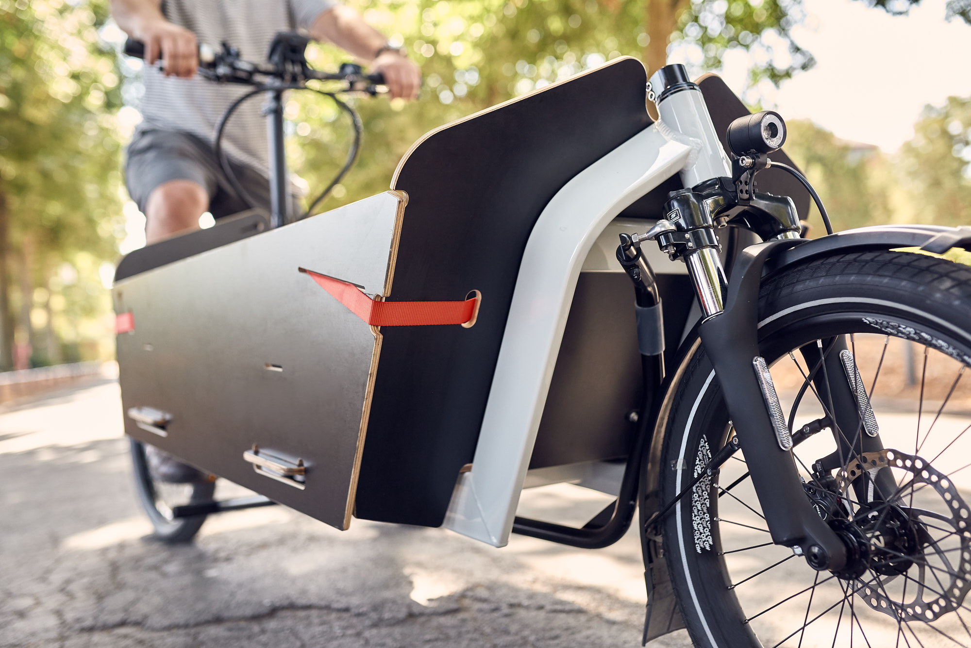 Eine männliche Person fährt auf einem weißen Lastenrad mit Transportbox 