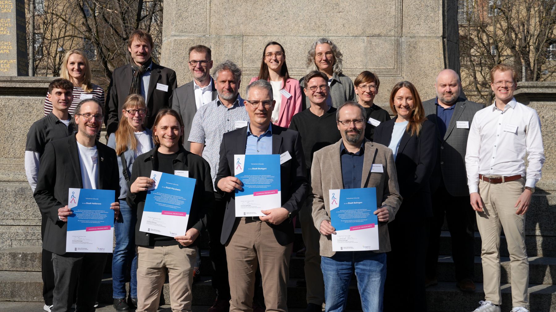 Gruppenbild mit Vertreter:innen des Ministeriums für Verkehr Baden-Württemberg und der im Modellprojekt "Gehwege freiräumen" ausgewählten Kommunen.